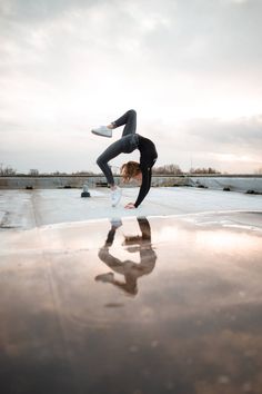 a woman doing a handstand on top of a skateboard in the air