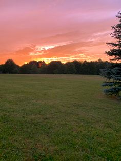 the sun is setting over an open field