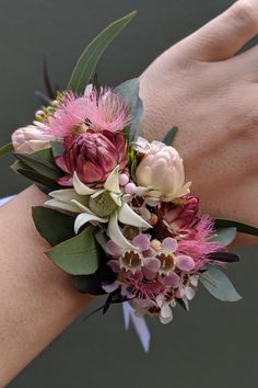 a wrist corsage with pink flowers and greenery