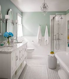 an image of a bathroom with white and blue decor on the walls, tub, sink, and shower