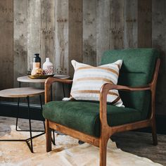 a green chair sitting next to a table with a white and brown pillow on it