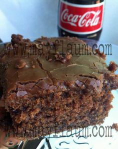 a close up of a piece of cake on a plate with a coca - cola bottle in the background