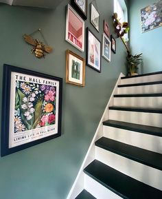 some pictures are hanging on the wall next to a stair case with black and white stairs