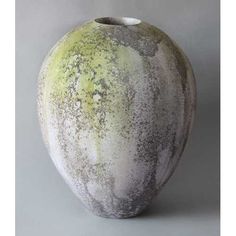 a gray and yellow vase sitting on top of a white table