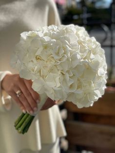 a woman holding a bouquet of white flowers