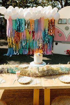 a table topped with a cake next to a vw camper van covered in streamers