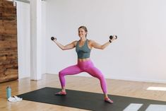 a woman is doing exercises with dumbbells on a mat in an empty room