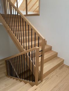 a wooden stair case next to a white wall