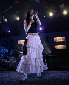 a woman in a skirt singing on stage