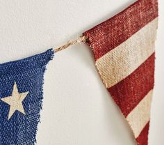 an american flag hanging on the wall next to a white wall with red, white and blue stripes