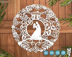 the laser cut wedding ornament is shown on a wooden background with greenery