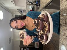 a woman standing in front of a counter with some food on top of her hands