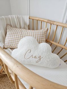 a white heart shaped pillow sitting on top of a wooden rocking chair next to pillows