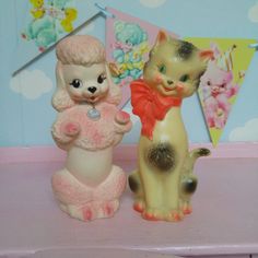 two little figurines sitting on top of a pink shelf