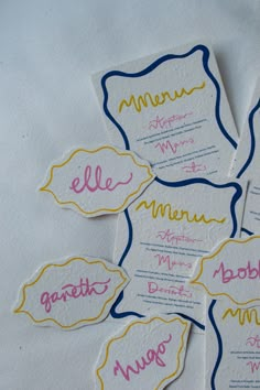 four different colored labels on white paper with yellow and blue trims are arranged in the shape of circles