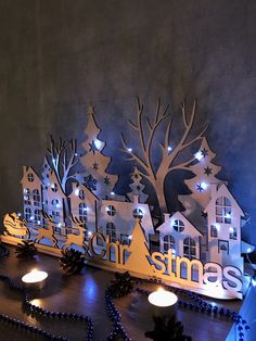 a lighted christmas scene with houses and trees on the side, surrounded by blue lights