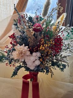 a vase filled with lots of flowers on top of a white cloth covered tablecloth