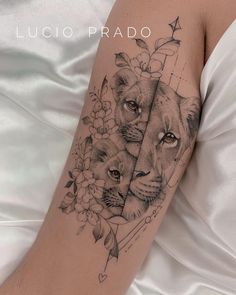 a woman's arm with two lions on it and flowers in the background,