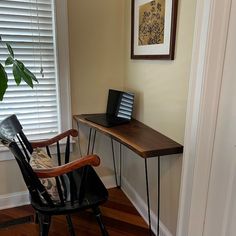 a wooden desk with a laptop computer on top of it next to a black chair