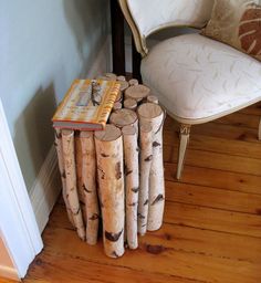 a stack of logs sitting on top of a wooden floor next to a white chair