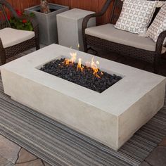 a fire pit sitting on top of a patio next to two chairs and a table