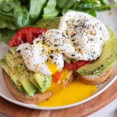 an open face sandwich with avocado, tomatoes and eggs on it sitting on a plate