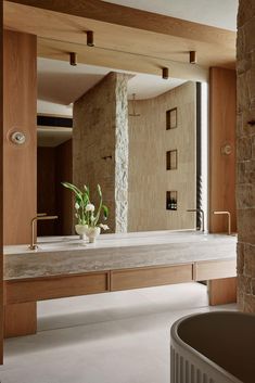 a bathroom with a stone wall and large mirror over the bathtub is seen from across the room