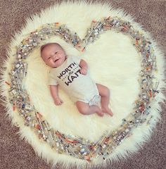 a baby is laying in the middle of a heart - shaped frame made out of glass beads