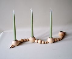 three candles are arranged in the shape of a long bead necklace with wooden beads