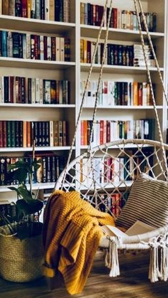 a white hanging chair in front of a bookshelf filled with lots of books