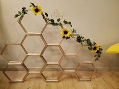 a wooden honeycomb with sunflowers and greenery on the sides, against a white wall