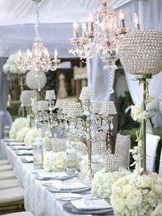 the tables are set with white flowers and crystal chandeliers