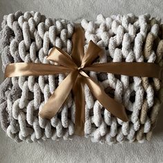 a blanket wrapped in white and brown yarn with a gold ribbon