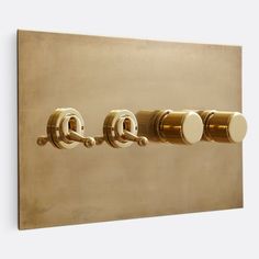 three knobs on the side of a gold wall mounted light switch with white buttons