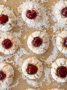 small pastries covered in powdered sugar and jelly sit on a baking sheet, ready to be eaten