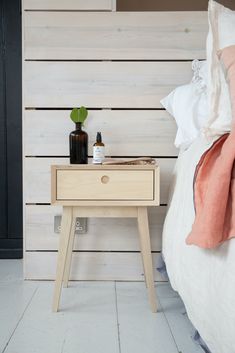 a bed with a wooden headboard next to a night stand and bottle on it