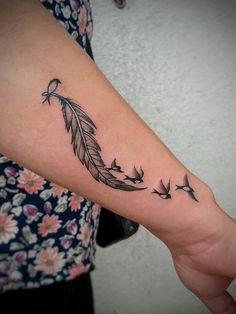 a woman's arm with a feather and birds tattoo on the left side of her arm