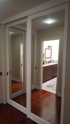 an empty room with large mirrors on the wall and wooden floors in front of it