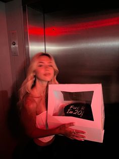 a woman holding up a box with a cake in it