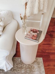 a white table with a magazine on it next to a couch