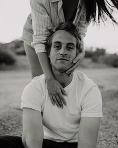 a man is sitting on the ground with his hand on his shoulder as another mans back