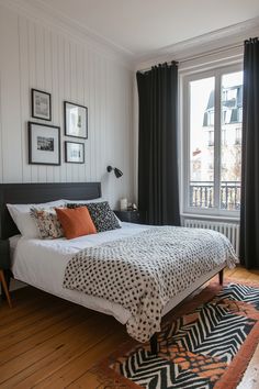 a bed sitting in a bedroom next to a window covered in black and white curtains