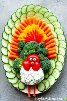 a plate with vegetables, carrots, cucumbers and a chicken face on it