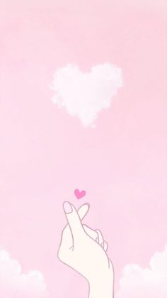 a hand holding a pink heart in the sky