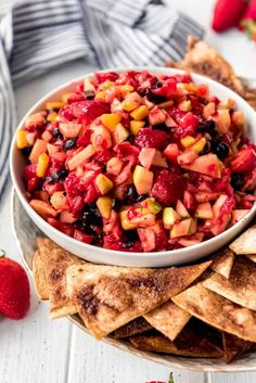 a white bowl filled with fruit salsa surrounded by tortilla chips