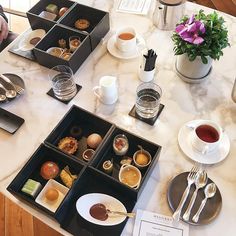 a table topped with trays filled with food and drinks next to a cup of coffee