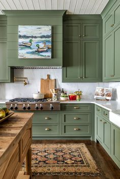 a kitchen with green cabinets and wooden counter tops, along with an area rug on the floor