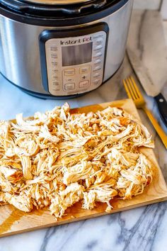 shredded chicken on a cutting board next to an instant pot