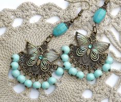 "Flirty chandelier earrings featuring filigree butterfly accents on embossed antiqued pendants that swing over dangling pale turquoise blue glass beads! Each of the butterflies are accented with painted touches of sea foam green & turquoise and little Swarovski crystal rhinestones sparkle in their centers! Each unique pendant dangles from genuine magnesite beads, too, which are thought to aid in meditation and creativity! Just dangle this unique pair from your ears to add fun, Boho style to Bohemian Dangle Jewelry With Butterfly Charm, Bohemian Jewelry With Butterfly Charm Dangle, Bohemian Butterfly Charm Jewelry For Jewelry Making, Bohemian Jewelry With Butterfly Charm For Jewelry Making, Bohemian Butterfly Jewelry With Pierced Design, Bohemian Butterfly Nickel-free Jewelry, Nickel-free Light Blue Bohemian Jewelry, Bohemian Light Blue Nickel-free Jewelry, Light Blue Bohemian Dangle Jewelry