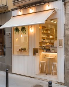 an outside view of a store with white awnings and stools in front of it